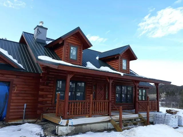 A log cabin with a porch and a black roof