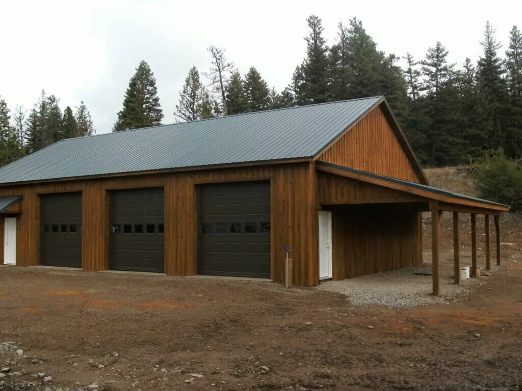 A wooden garage with a metal roof and black garage doors
